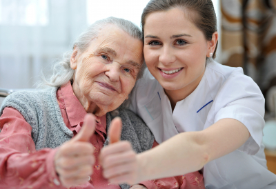 senior woman and her caregiver giving a thumbs up