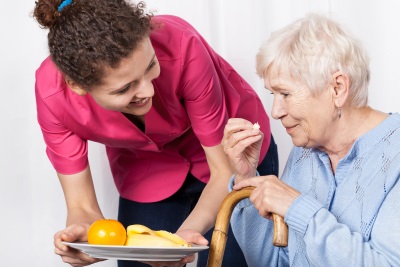 caregiver serving healthy food to a senior woman