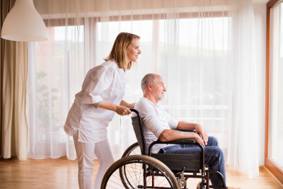 Nurse and senior man in wheelchair during home visit.
